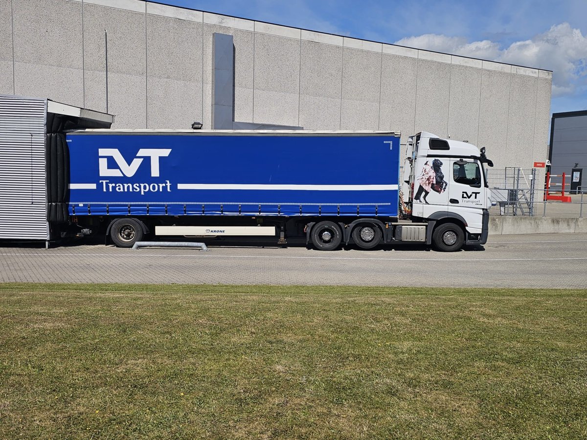LVT white tractor and blue trailer beside a distribution building